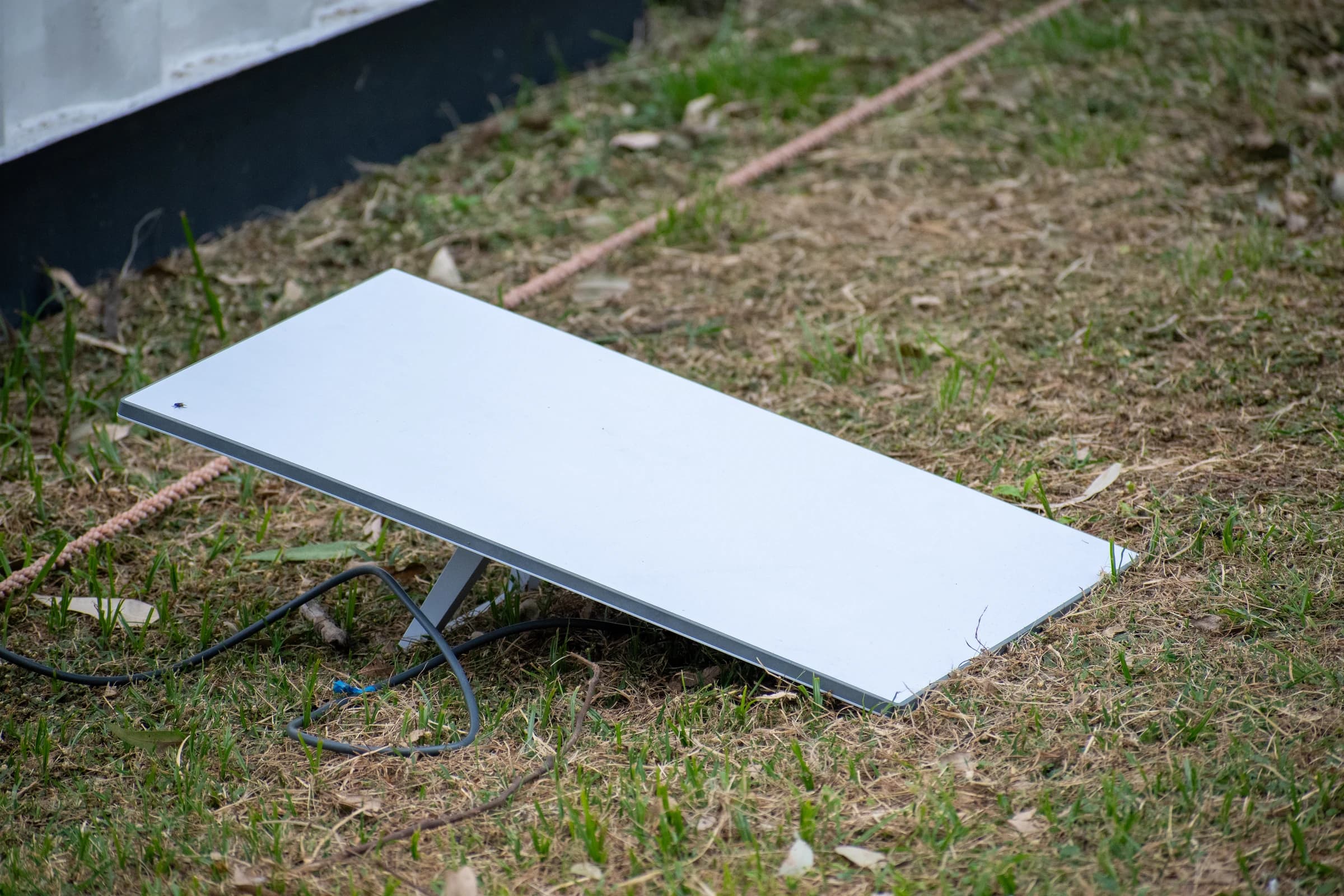 A rectangular Starlink user terminal placed on grass at Club San Albano in Burzaco, Argentina