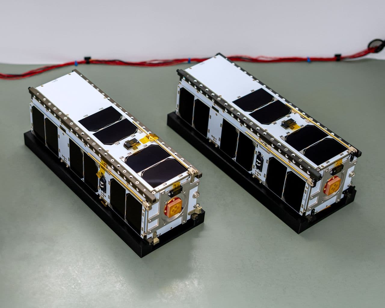Pair of compact satellite platforms representing high-value spacecraft subsystems and payload integration