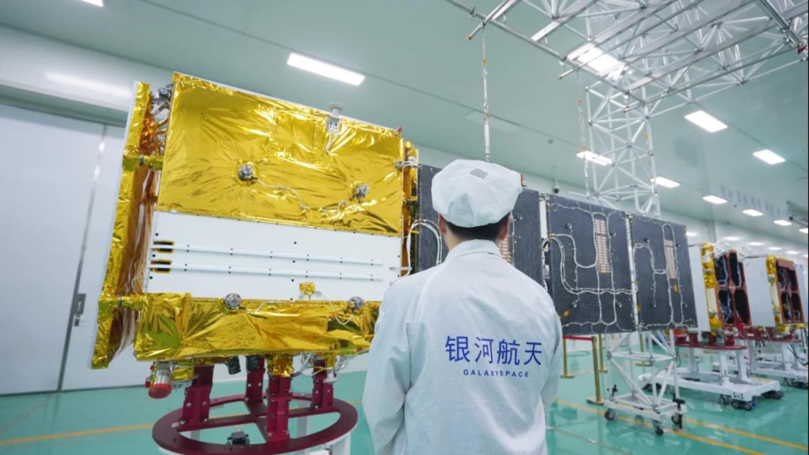 A GalaxySpace engineer inspecting batch-built satellites in a clean room